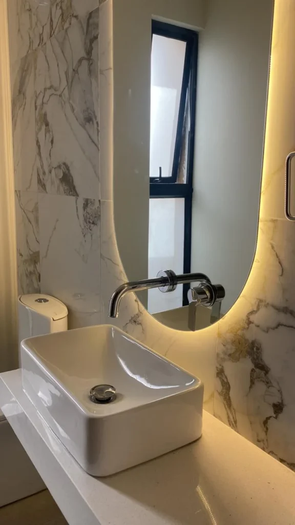 Diseño de baño moderno con lavamanos sobre encimera y espejo retroiluminado en Arequipa